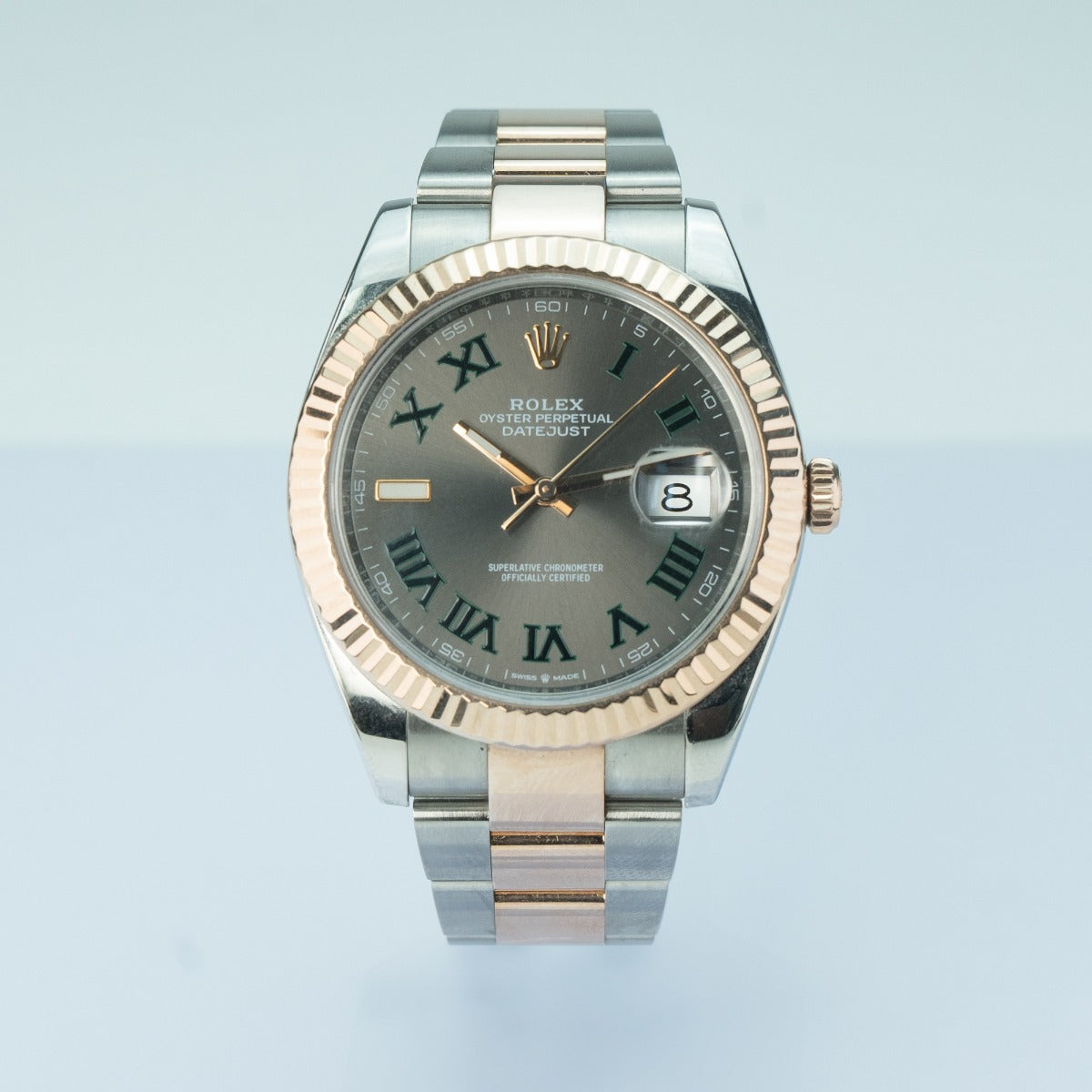 Rolex watch with silver and rose gold band on light blue background